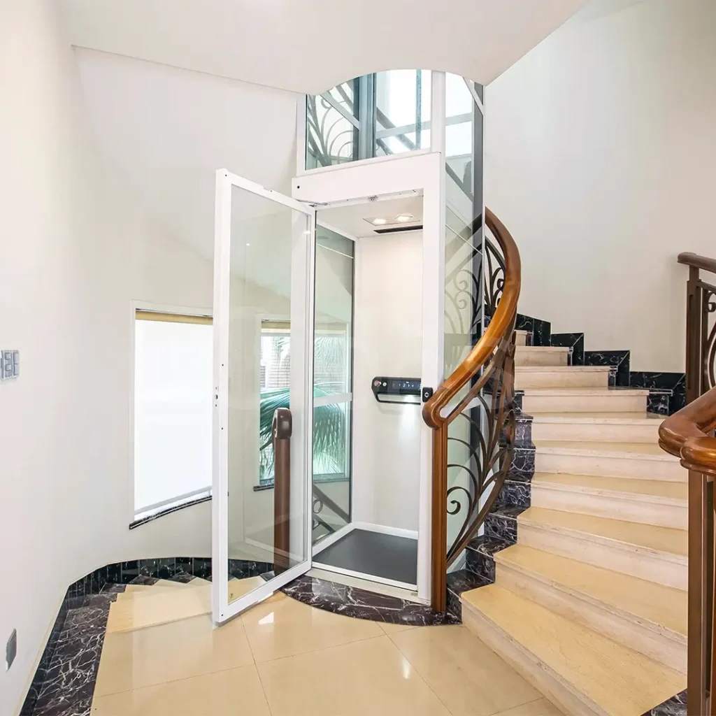 Why Is Space-Saving Important When Choosing a Home Lift in the UAE? 2 Cibes V90 home lift installed in a curved staircase with glass shaft and white frame.