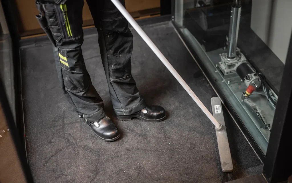 Technician cleaning the home lift pit area during regular lift maintenance.